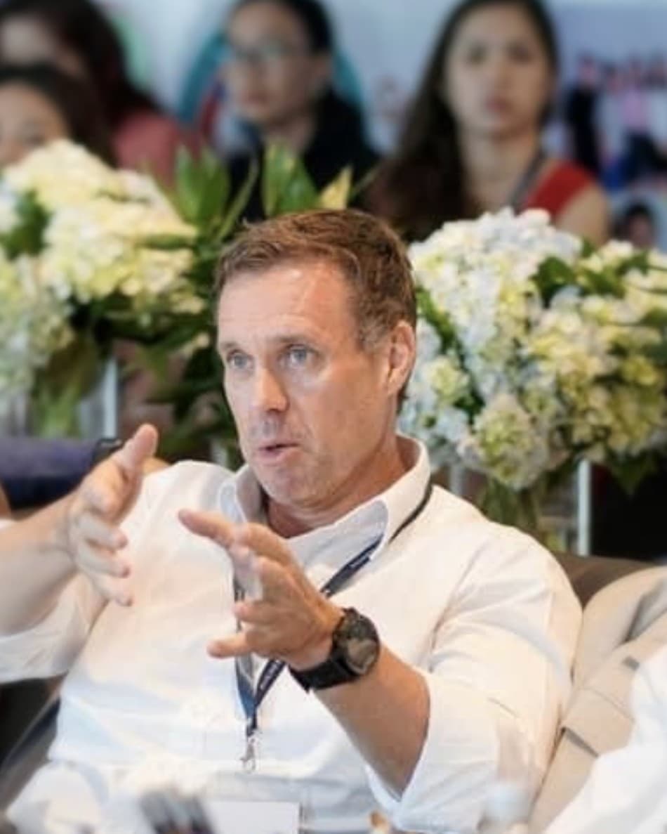 Gary Malcolm in discussion at an executive roundtable, gesturing as he makes a point